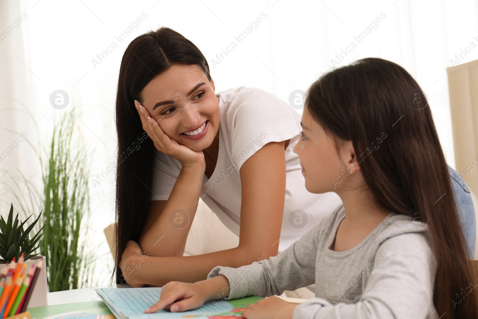 Photo of Happy mother and daughter reading book together at home. Single parenting