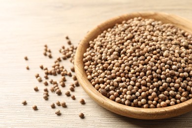 Dried coriander seeds in bowl on wooden table, closeup