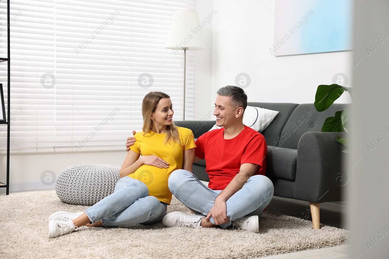 Photo of Young family housing concept. Pregnant woman with her husband on floor at home