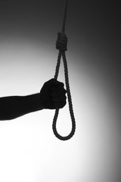 Photo of Silhouette of man holding rope noose on light background, closeup