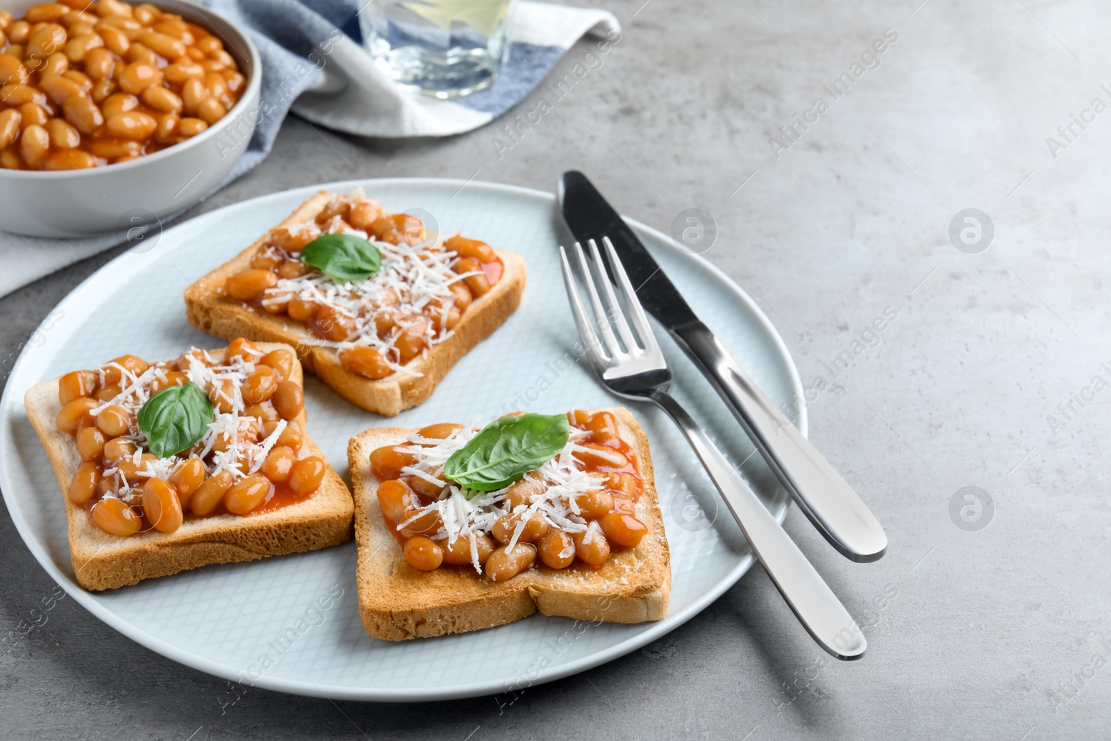 Photo of Toasts with delicious canned beans on light grey table