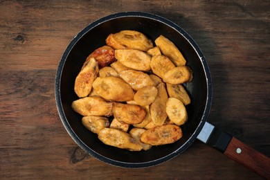 Photo of Tasty deep fried banana slices on wooden table, top view