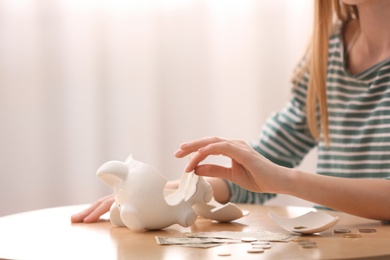 Photo of Teen girl with broken piggy bank and money at home, closeup