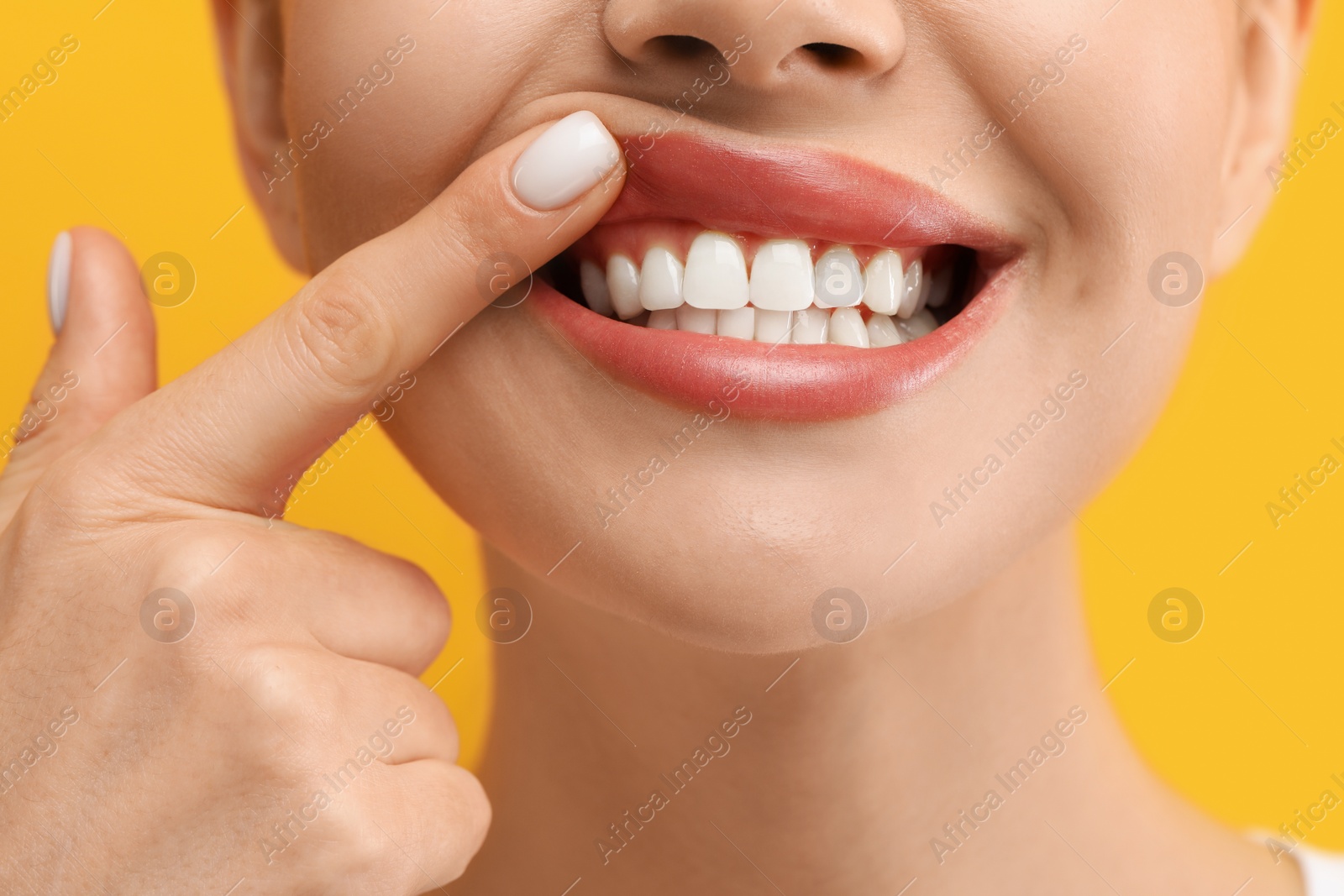 Photo of Woman showing her clean teeth on yellow background, closeup