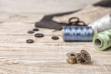 Composition with threads and sewing accessories on wooden background