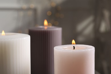 Photo of Different burning candles on blurred background, closeup