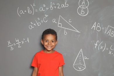 Photo of Little African-American school child and mathematical formulas on grey background