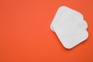 Photo of Clean cotton pads on orange background, flat lay. Space for text