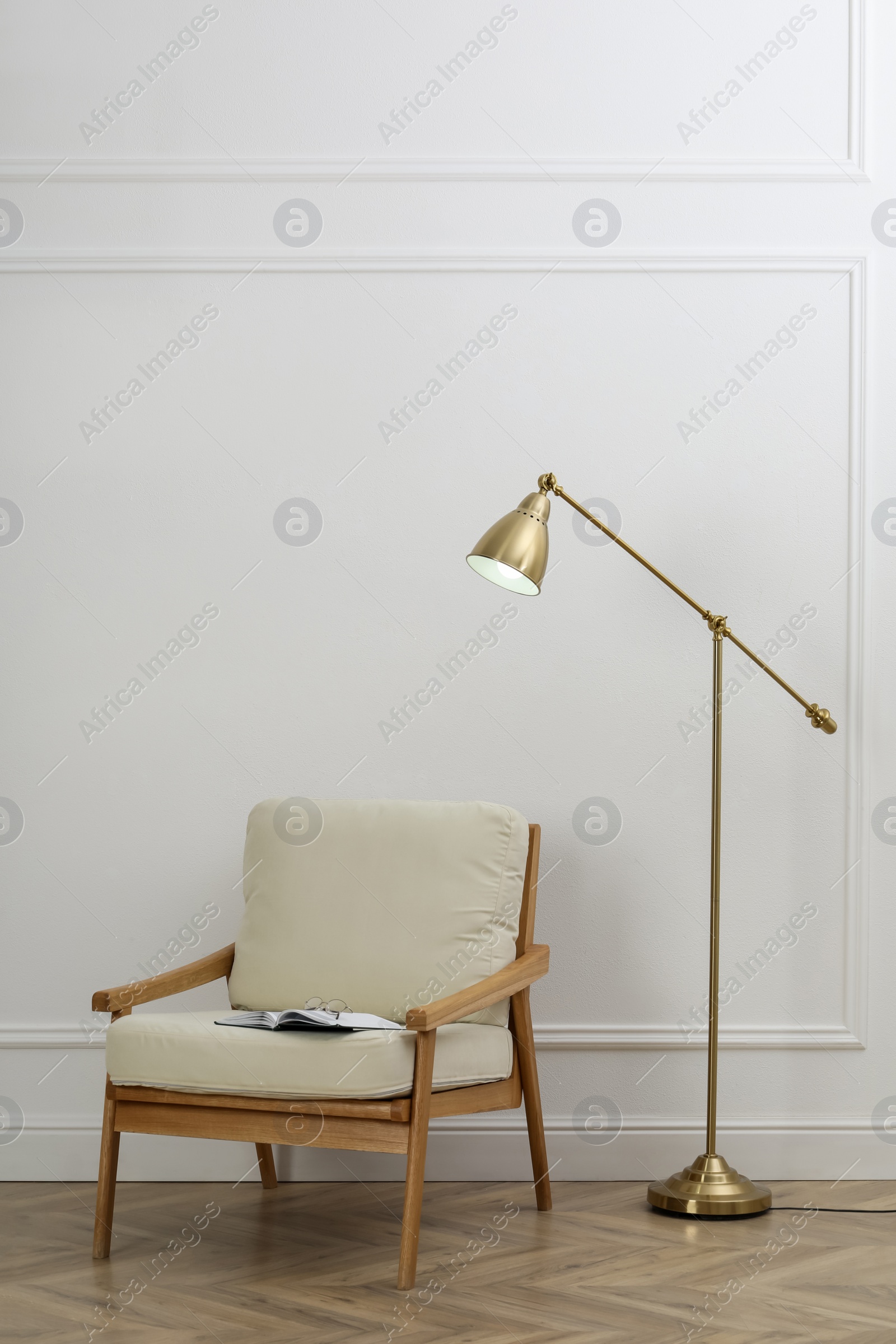 Photo of Stylish room interior with lamp and armchair near white wall