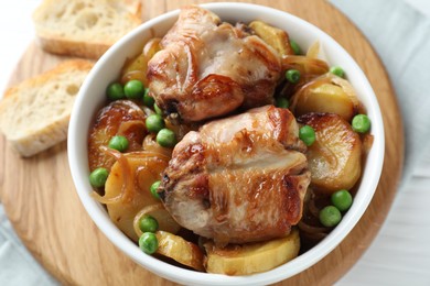 Photo of Tasty cooked rabbit with vegetables in bowl and bread on table, above view
