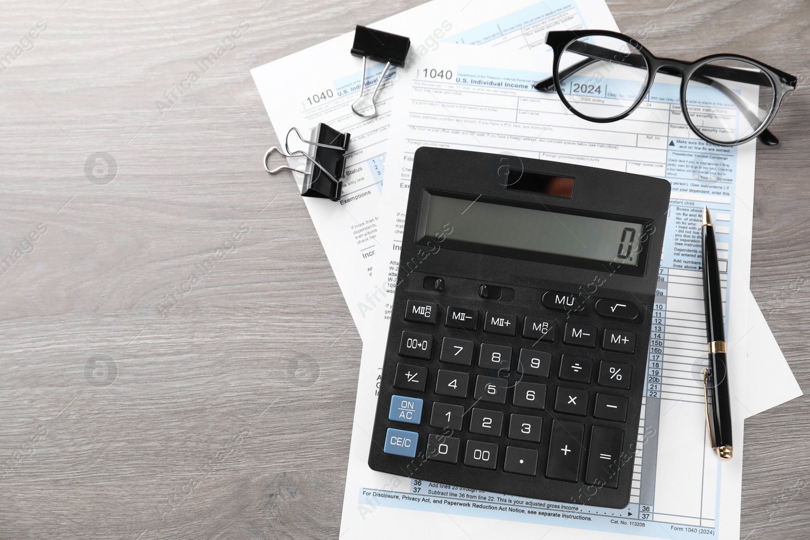 Photo of Tax accounting. Calculator, documents, glasses and stationery on wooden table, flat lay