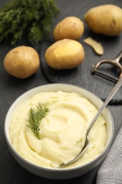 Photo of Freshly cooked homemade mashed potatoes and raw vegetables on dark grey table, closeup