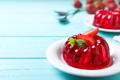 Delicious red jelly with strawberry and mint on light blue wooden table. Space for text