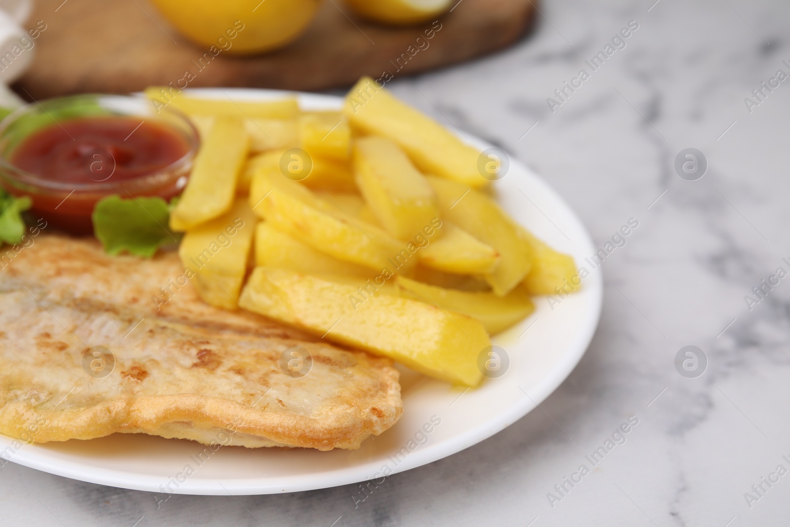 Photo of Delicious fish and chips with ketchup and lettuce on light table, closeup