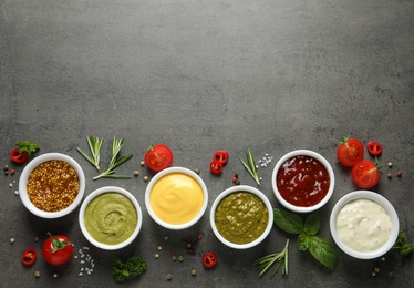 Photo of Bowls with different sauces and ingredients on gray background, flat lay. Space for text