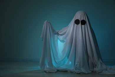 Creepy ghost. Woman covered with sheet on dark teal background, space for text