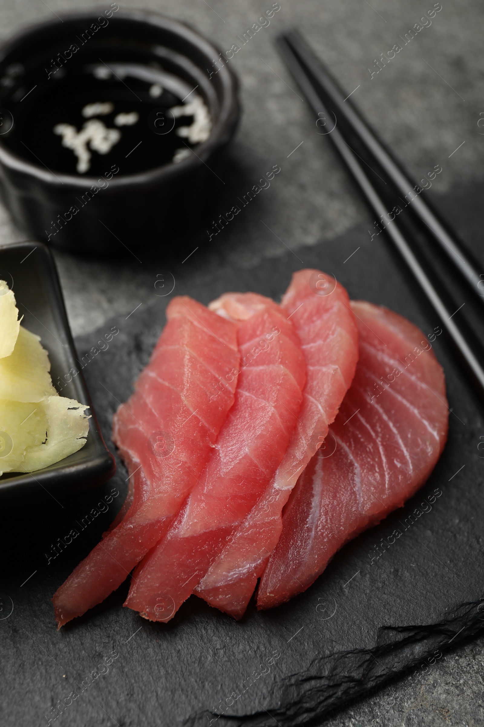 Photo of Tasty sashimi (pieces of fresh raw tuna) on black board, closeup