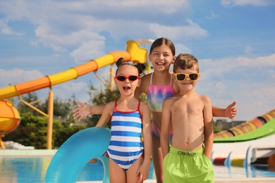Cute little children with inflatable ring near pool in water park