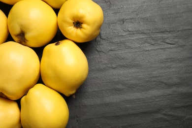 Photo of Fresh ripe organic quinces on black table, flat lay. Space for text