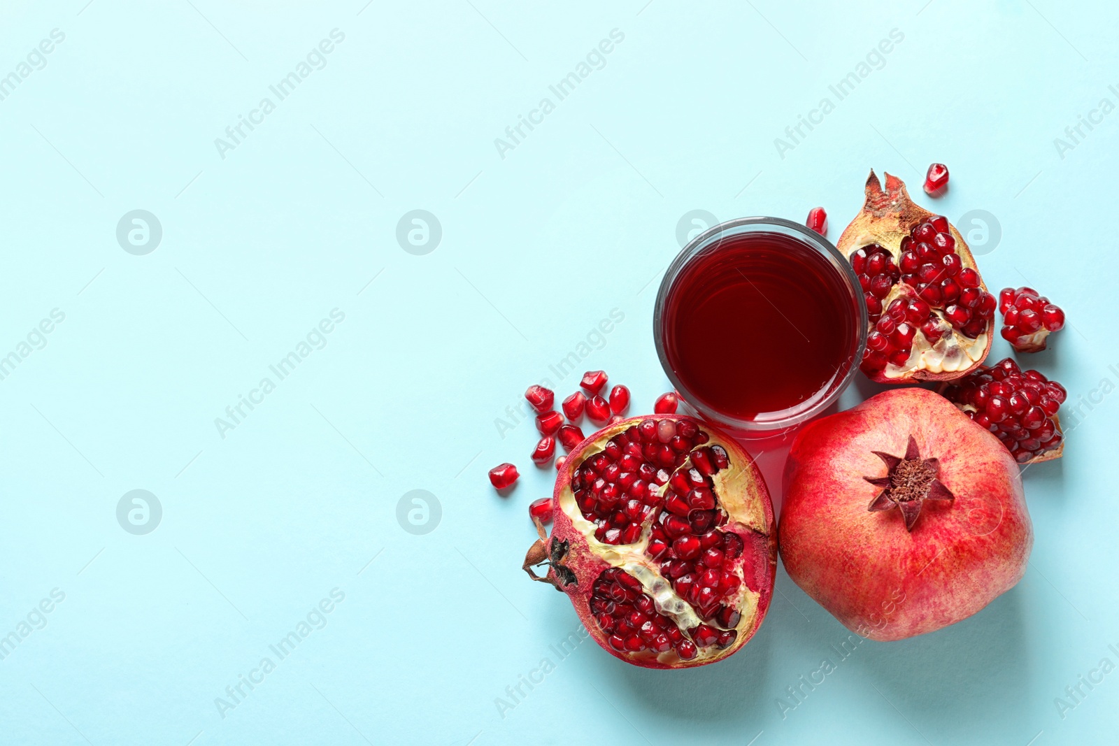 Photo of Glass of pomegranate juice and fresh fruits on color background, top view with space for text