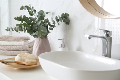 Photo of Fresh eucalyptus branches and bathroom items on countertop