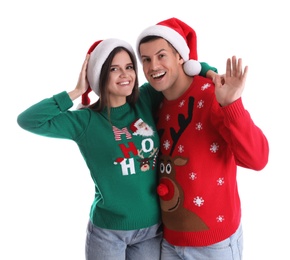 Photo of Beautiful happy couple in Santa hats and Christmas sweaters on white background