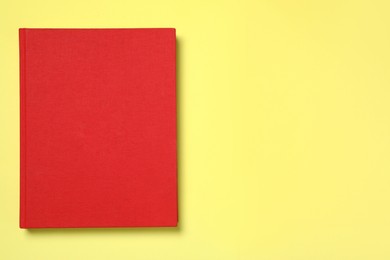 Photo of Book with red cover on yellow background, top view. Space for text