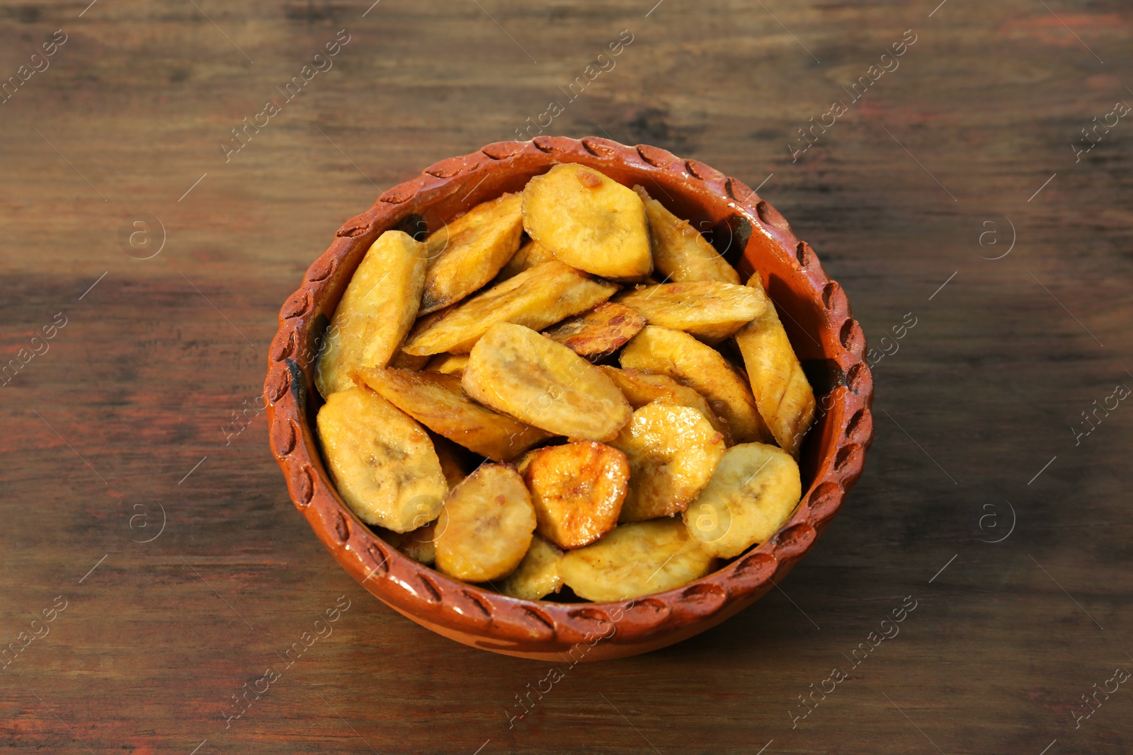 Photo of Tasty deep fried banana slices on wooden table