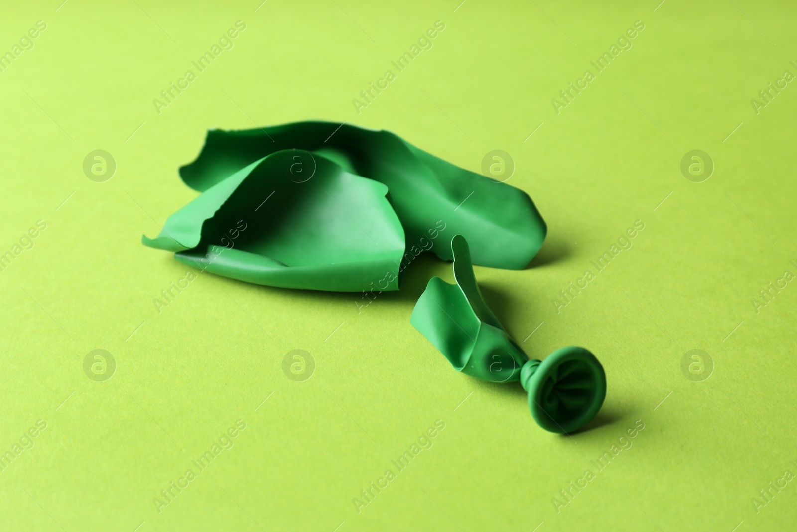 Photo of Popped green latex balloon on color background