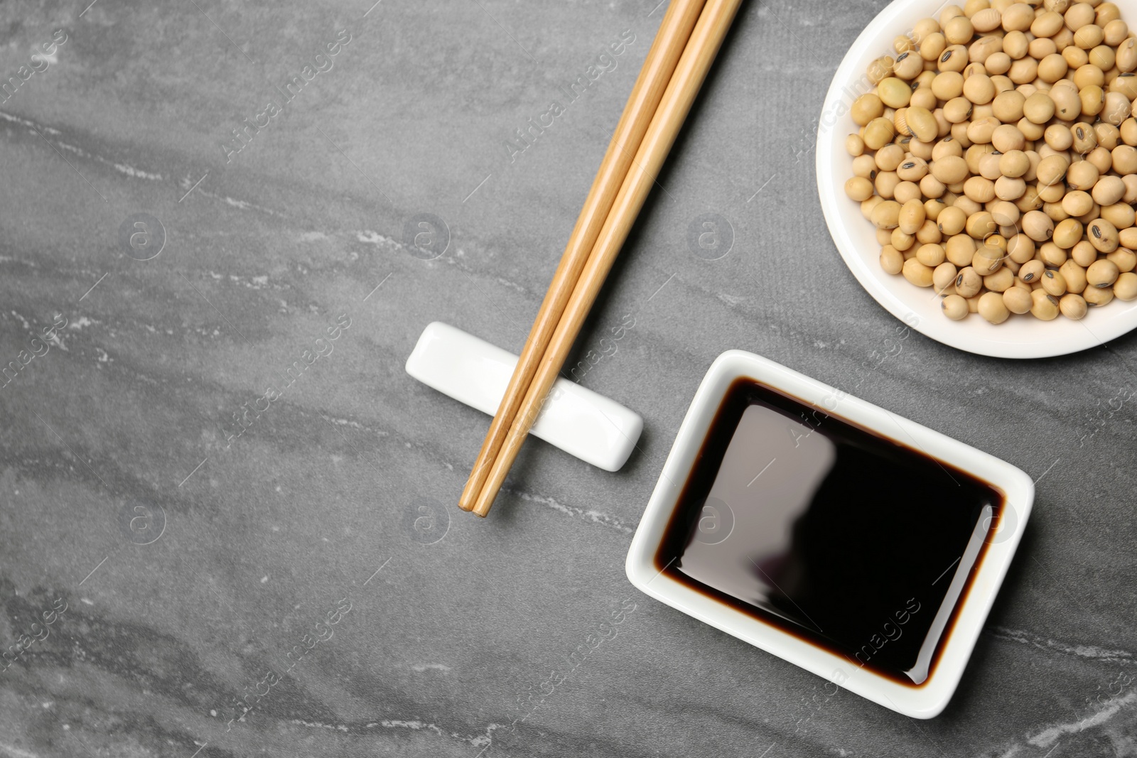 Photo of Flat lay composition with soy sauce and beans on grey table. Space for text