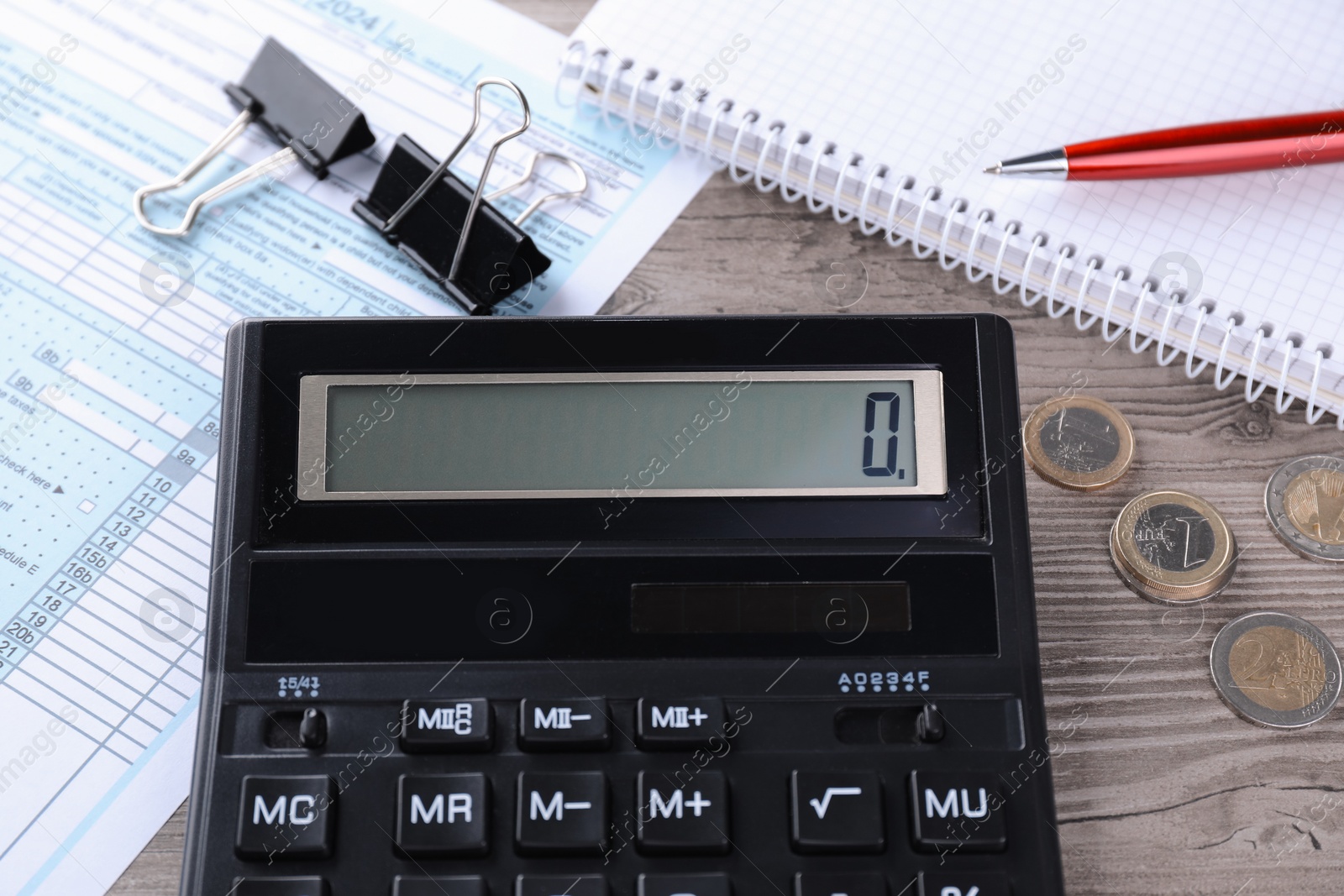 Photo of Tax accounting. Calculator, document, stationery and coins on wooden table, closeup