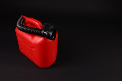 Photo of New red plastic canister on black background. Space for text