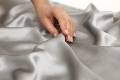 Woman touching smooth silky fabric, closeup view