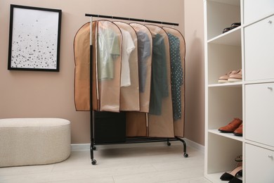 Garment bags with clothes hanging on rack in room