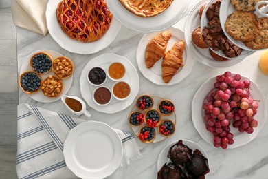 Variety of snacks on white marble table in buffet style, flat lay