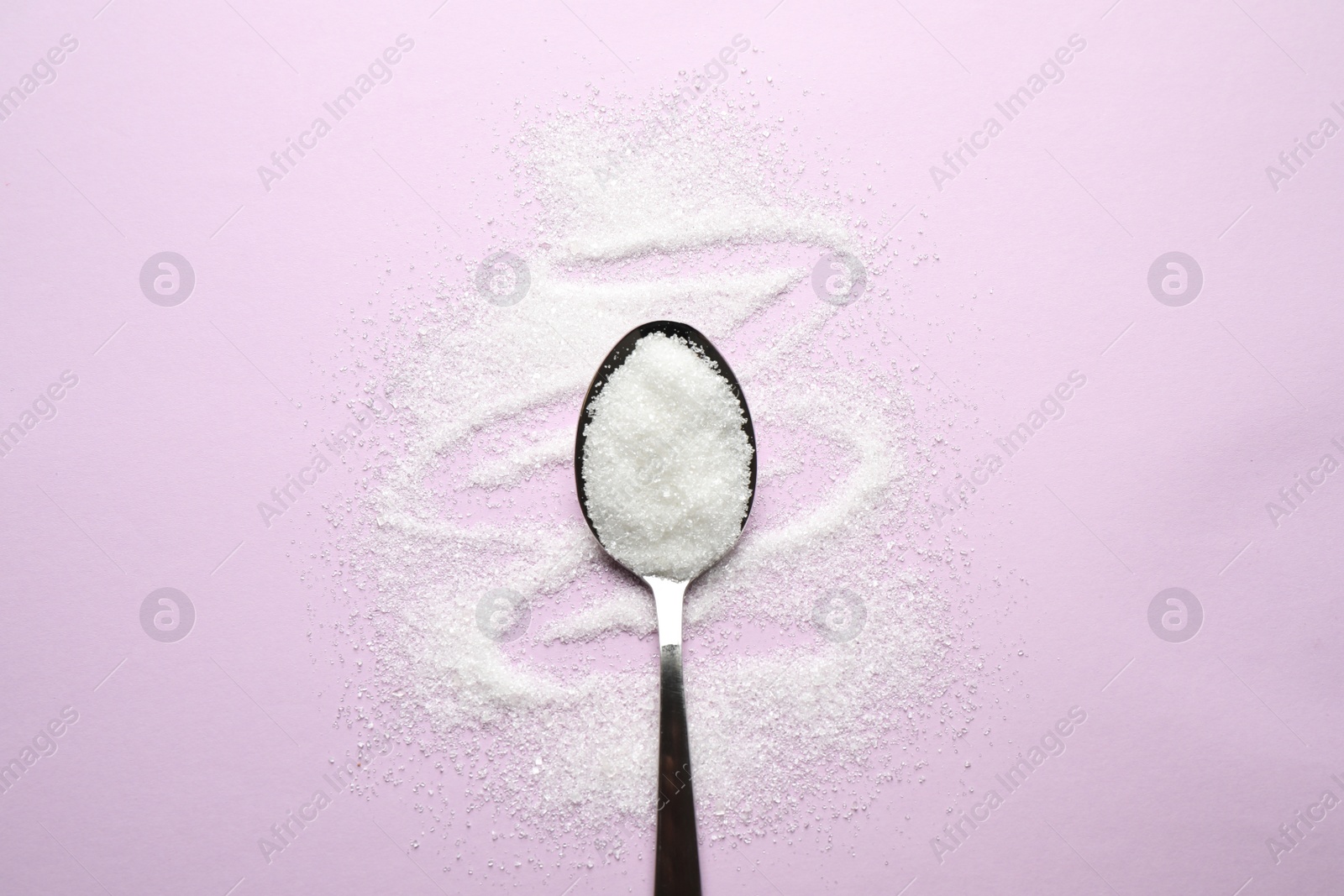 Photo of Granulated sugar and spoon on lilac background, flat lay