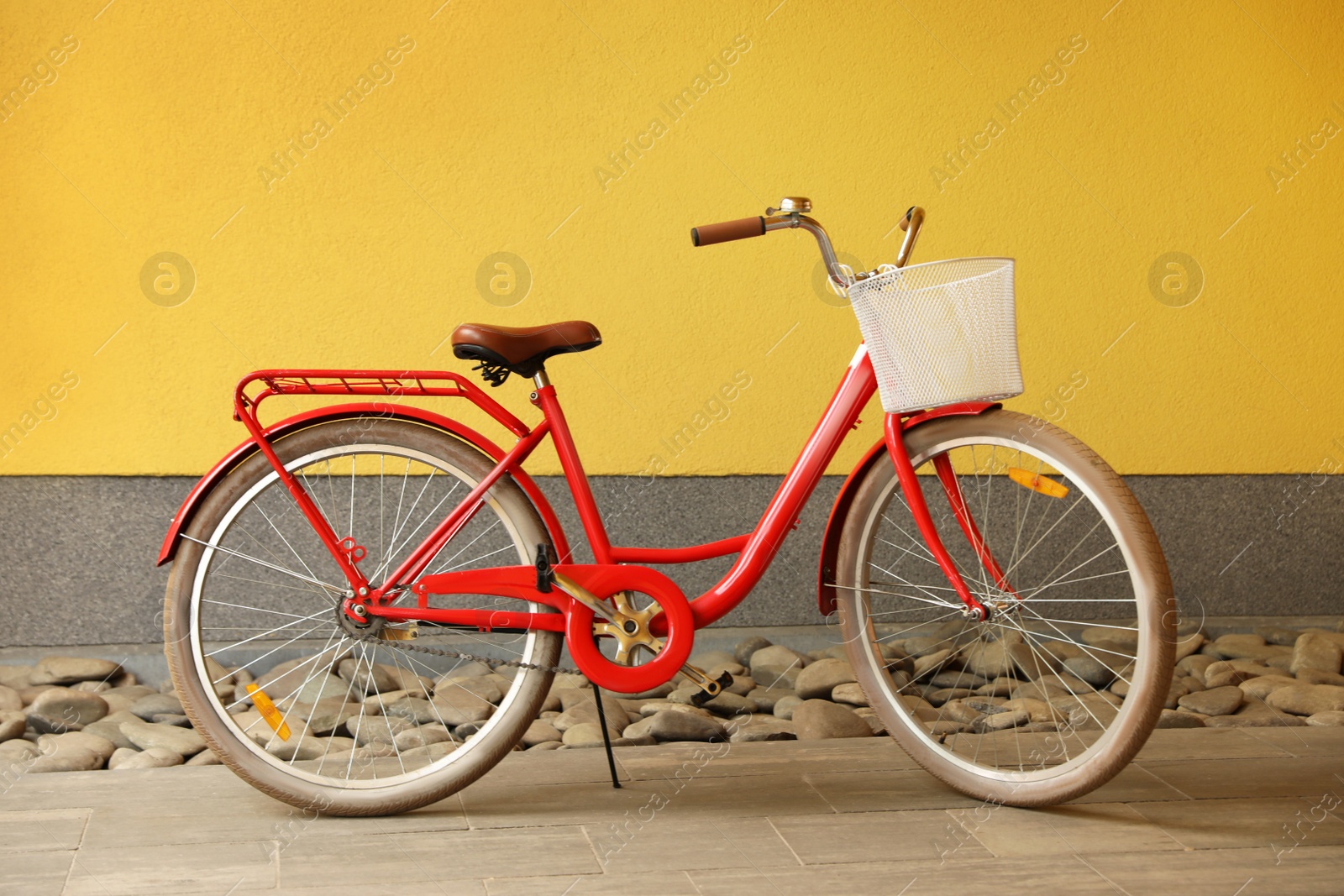 Photo of Modern color bicycle with basket near wall outside