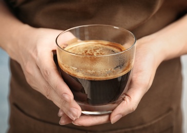 Woman holding glass of aromatic hot coffee, closeup