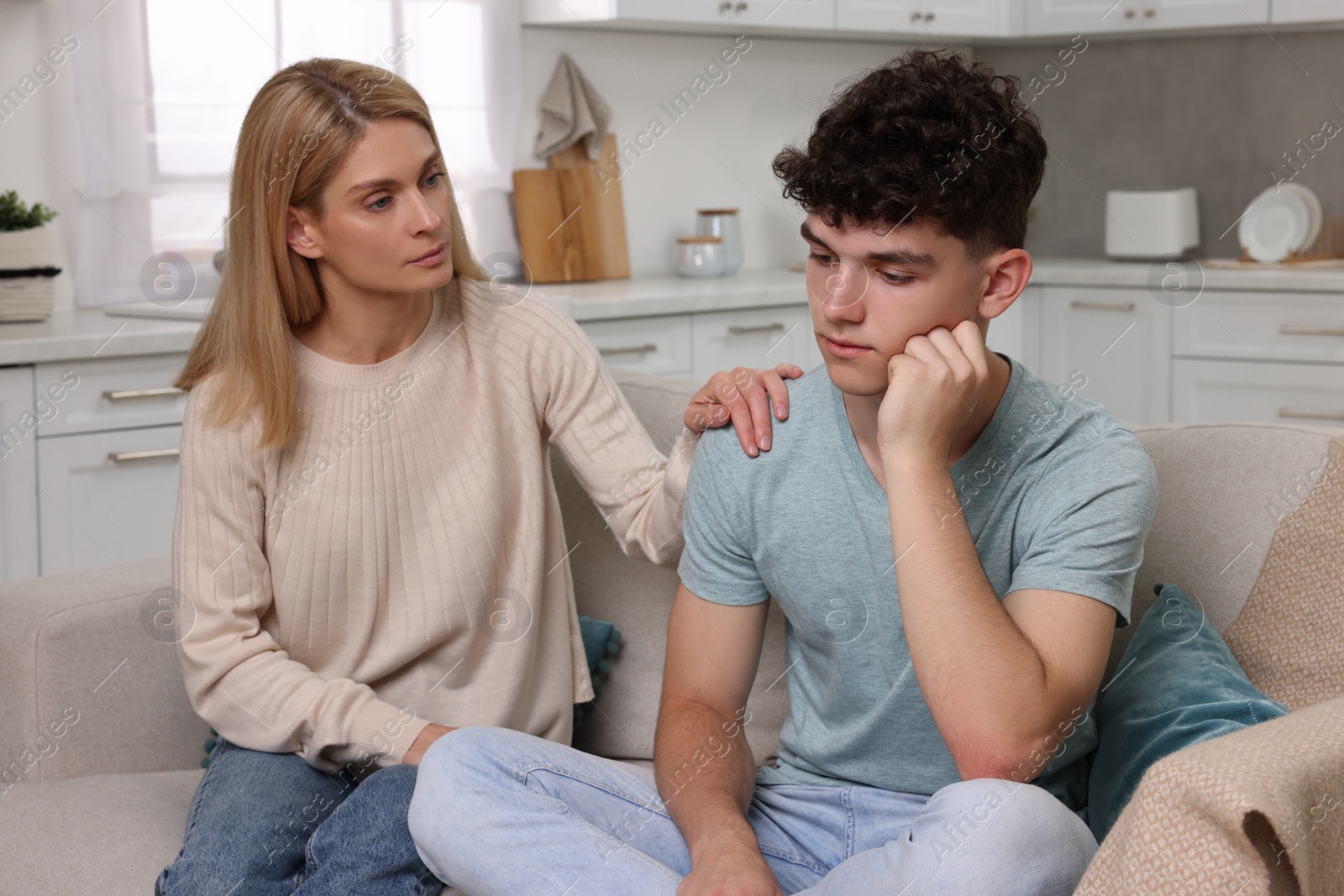 Photo of Mother consoling her upset son at home. Teenager problems