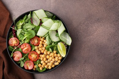 Tasty salad with chickpeas, cherry tomatoes and cucumbers on grey textured table, top view. Space for text