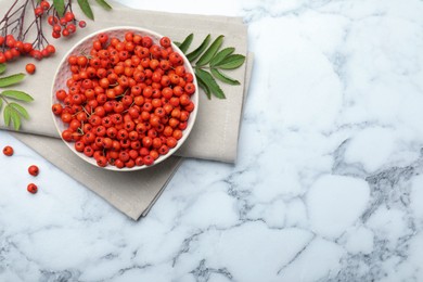 Photo of Fresh ripe rowan berries and leaves on white marble table, flat lay. Space for text