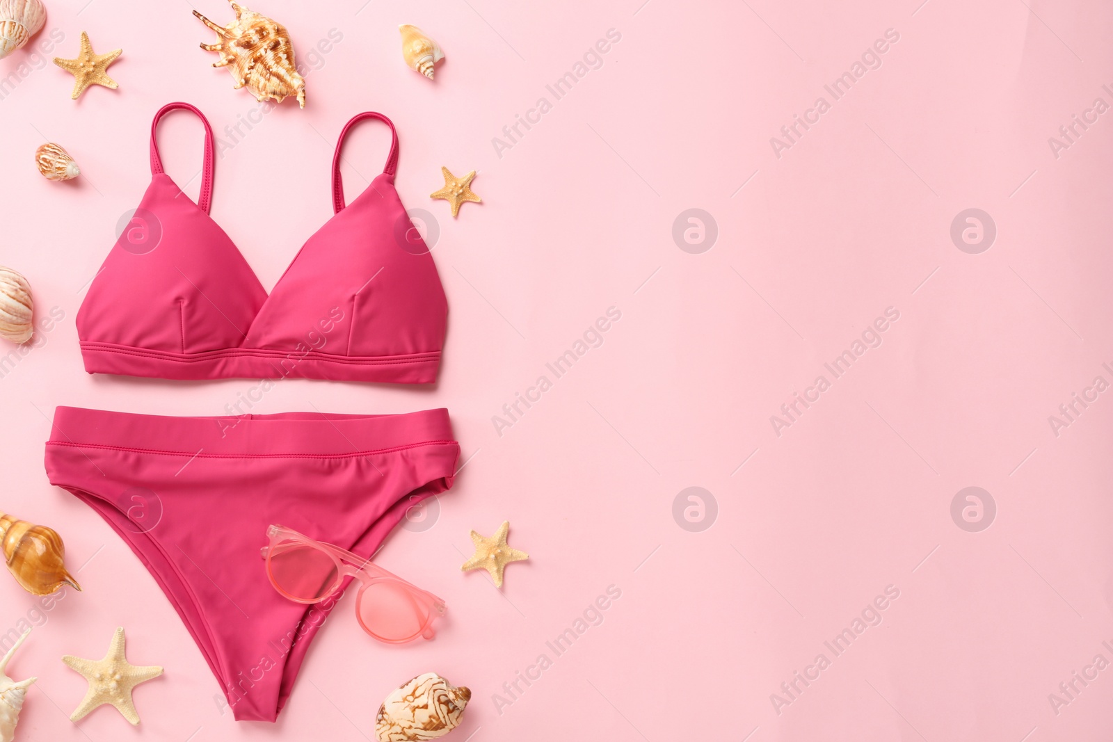 Photo of Stylish bikini and beach accessories on pink background, flat lay. Space for text