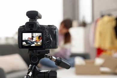 Photo of Fashion blogger showing her shoes while recording video at home, focus on camera