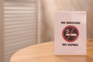 Photo of No Smoking sign on wooden table indoors, space for text