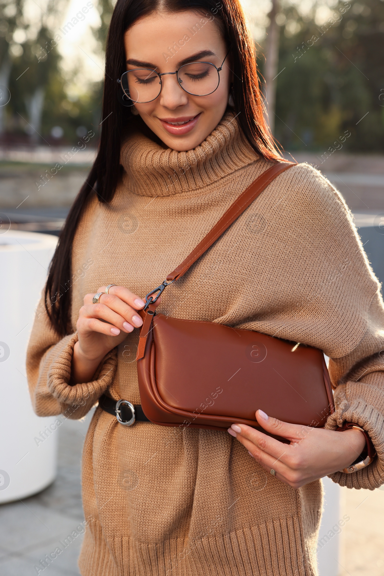 Photo of Fashionable young woman with stylish bag on city street