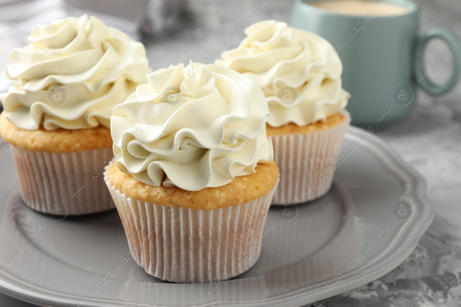 Photo of Tasty cupcakes with vanilla cream on grey table, closeup