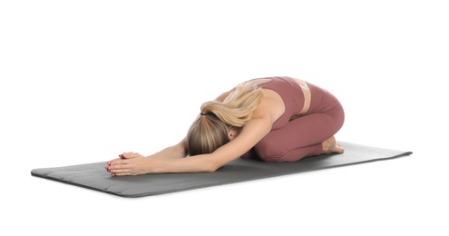 Young woman in sportswear practicing yoga on white background