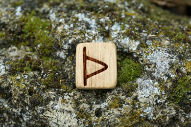 Photo of Wooden rune Thurisaz on stone with moss outdoors, closeup