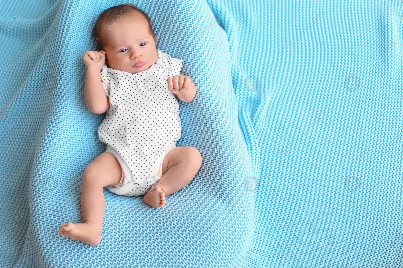 Photo of Cute little baby lying on light blue plaid, top view. Space for text
