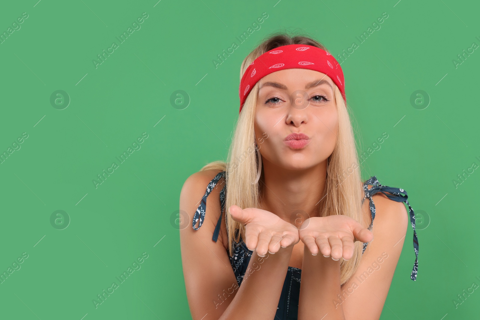 Photo of Portrait of beautiful hippie woman blowing kiss on green background. Space for text